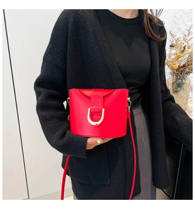 Detail of red bucket bag featuring gold D-ring buckle and elegant shoulder strap