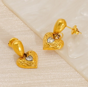 Detail of gold-plated heart earrings with hammered texture and sparkling center stone