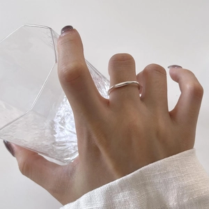 Minimalist 925 sterling silver irregular wave ring on hand holding a glass cup
