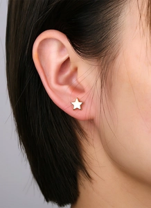 Close-up of minimalist gold-plated star stud earring worn on a model's earlobe