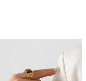 Detail of adjustable gold safety pin ring with dark inlay worn on a model finger