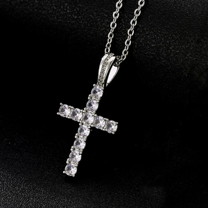 Macro shot of silver cross pendant with sparkling zircons on black leather background