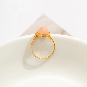 Detailed macro of handmade wire wrapped gold ring with round pink opal bead