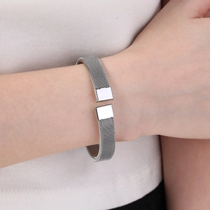 Dettaglio del bracciale rigido aperto in maglia intrecciata argento sul polso di donna