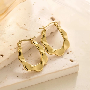Détail des boucles d'oreilles créoles vagues en acier titane plaqué or 18k sur pierre