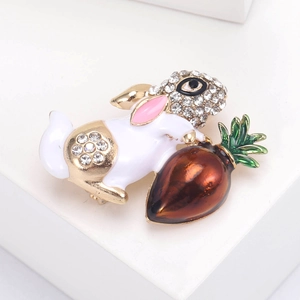 Close-up of white enamel rabbit brooch with carrot and rhinestone details on gold-tone metal