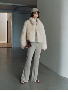 Chic cream faux fur vest styled with casual flared trousers in a minimalist modern interior