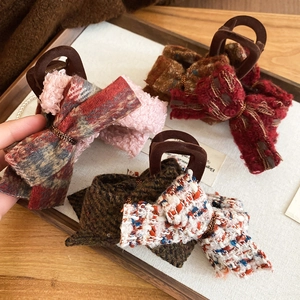 Detailed view of tweed bow hair claws in pink, burgundy, brown, and floral colors