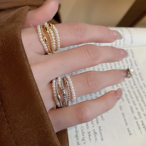 Close-up of elegant gold-plated layered pearl ring on hand with aesthetic book background