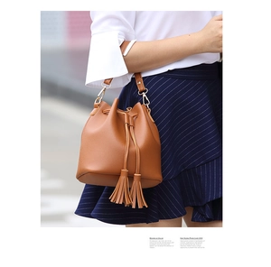 Close-up of brown PU leather bucket bag featuring decorative tassels and drawstring closure