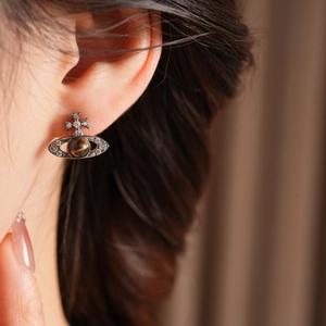 Détail des boucles d'oreilles Saturne avec œil de tigre et cristaux sur le mannequin