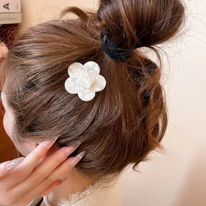 Elegant white acetate flower hair clip with marble texture worn on brown hair