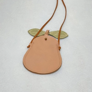 Detail of pink pear-shaped kids bag with lychee texture and green leaves