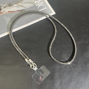 Close-up of black metal and crystal crossbody phone strap with transparent pad on leather