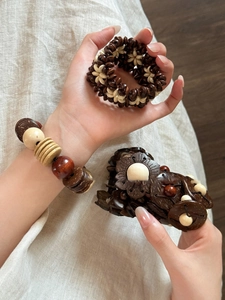 Detail of bohemian coconut shell and wooden beaded elastic bracelets on model's wrist