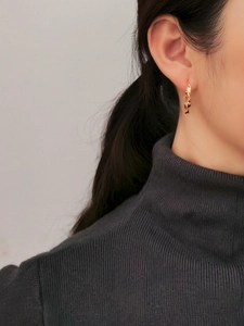 Dettaglio di orecchini a cerchio in argento S925 dorato con design a onde intrecciate