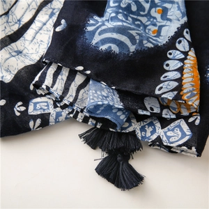 Detail of bohemian printed scarf showing intricate blue patterns and woven fringe trim