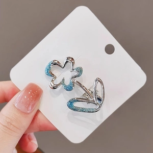 Macro shot of silver alloy flower hair clip with blue enamel detail on white card