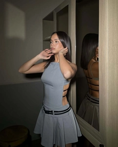 Détail de la robe plissée dos nu bleu-gris avec découpes latérales et lanières noires