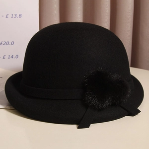 Detail of a black wool felt bowler hat featuring a soft faux fur heart-shaped pompom