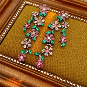 Gros plan de boucles d'oreilles vintage à fleurs avec strass roses et verts encadrés