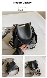 Detail of black bucket bag featuring golden hardware and a wide black and white strap