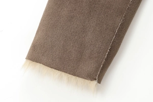 Detailed view of brown fabric and soft cream faux fur trim on a reversible long coat