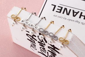 Detail of six pairs of infinity symbol pearl earrings in gold and silver finishes