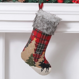 Plaid Christmas stocking with plush trim and tree patches hanging on a white fireplace