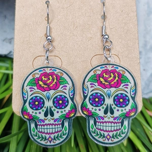 Nahaufnahme bunter Acryl-Ohrringe mit Totenkopf und Blumenmustern auf einer Karte