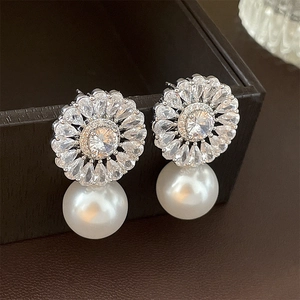 Macro view of flower-shaped zircon earring with a large white hanging pearl detail