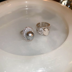 Close-up of luxury pearl and oval gemstone rings with intricate micro-pave diamond settings
