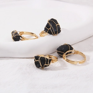 Detailed shot of four wire-wrapped rings with irregular raw black stones on ceramic tray