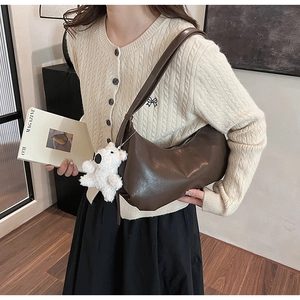 Detail of dark brown crescent PU leather bag with cute white bear plush charm on strap