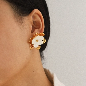 Close-up of gold and white flower stud earring worn by model showing exquisite 3D petal details