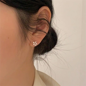 Close-up of minimalist 925 sterling silver flower stud earring worn on model's ear
