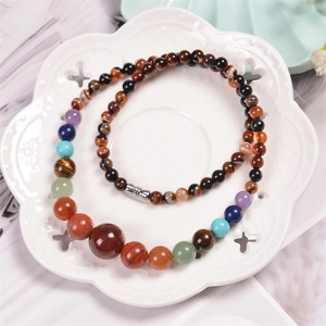 Macro detail of colorful natural stone beaded necklace on a white petal ceramic plate