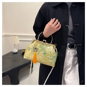 Detail of yellow silk Chinese style shell bag with floral embroidery and butterfly tassel