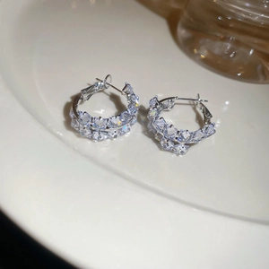 Close-up of silver hoop earrings with sparkling cubic zirconia crystals on a white tray
