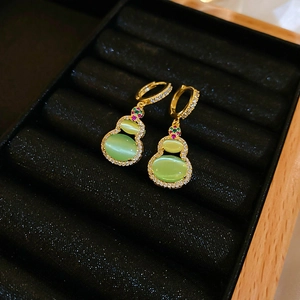 Close-up of gold-plated gourd earrings with green cat-eye stone and cubic zirconia inlay