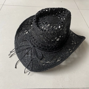 Detailed top view of black woven straw cowboy hat featuring fringe tassel and openwork pattern