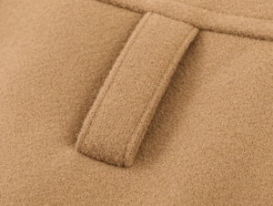 Detailed close-up of camel wool coat fabric texture and belt loop stitching quality