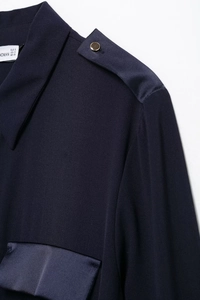 Close-up of shoulder epaulettes with metal button and satin stitching on dark blue dress
