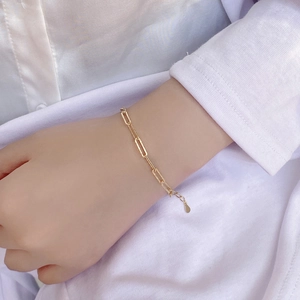 Detail of a gold-plated paperclip chain bracelet on wrist with adjustable extension link