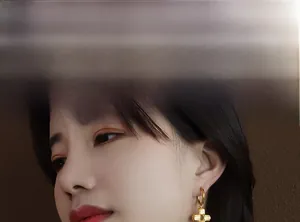 Detail view of a model wearing gold cross earrings with vertical textured engraving