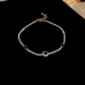 Bracelet argenté avec pierres émeraude et serti de cristaux sur fond noir en gros plan