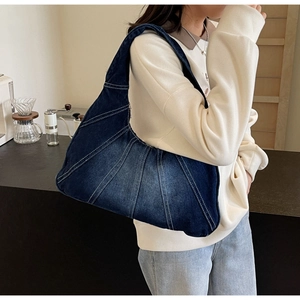 Détail du grand sac à bandoulière en denim avec surpiqûres blanches sur un mannequin