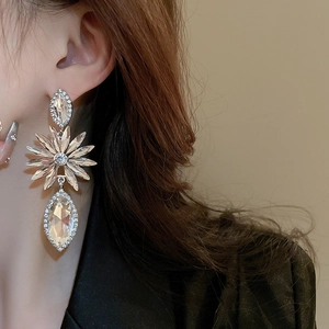 Detail of luxury teardrop drop earring with shimmering crystals on model ear