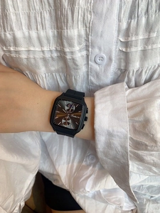 Close-up of a stylish square black dial watch with silicone strap on woman's wrist