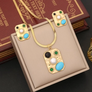 Vintage gold jewelry set with turquoise accents and white pearl on a display stand